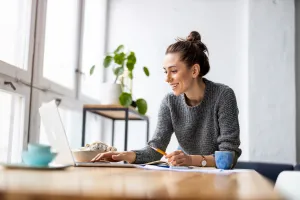 Woman smiling and using a laptop at a table